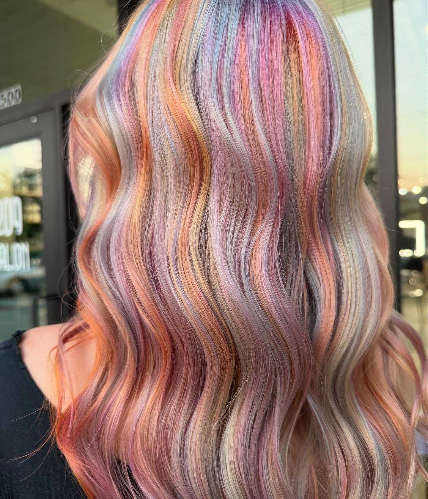 Rainbow-colored hair in soft waves outside a salon.