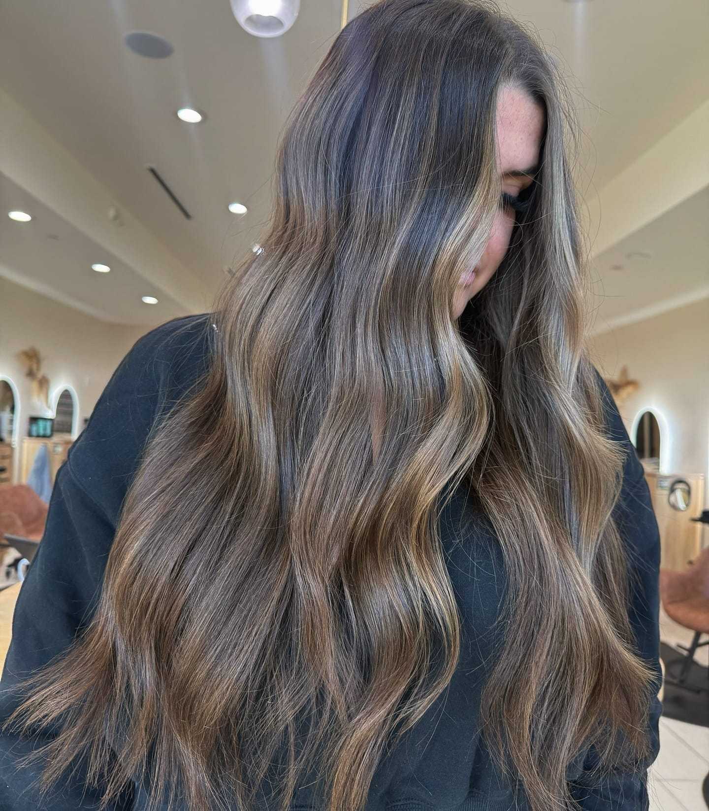 Long, wavy brown hair with highlights styled in a salon setting.