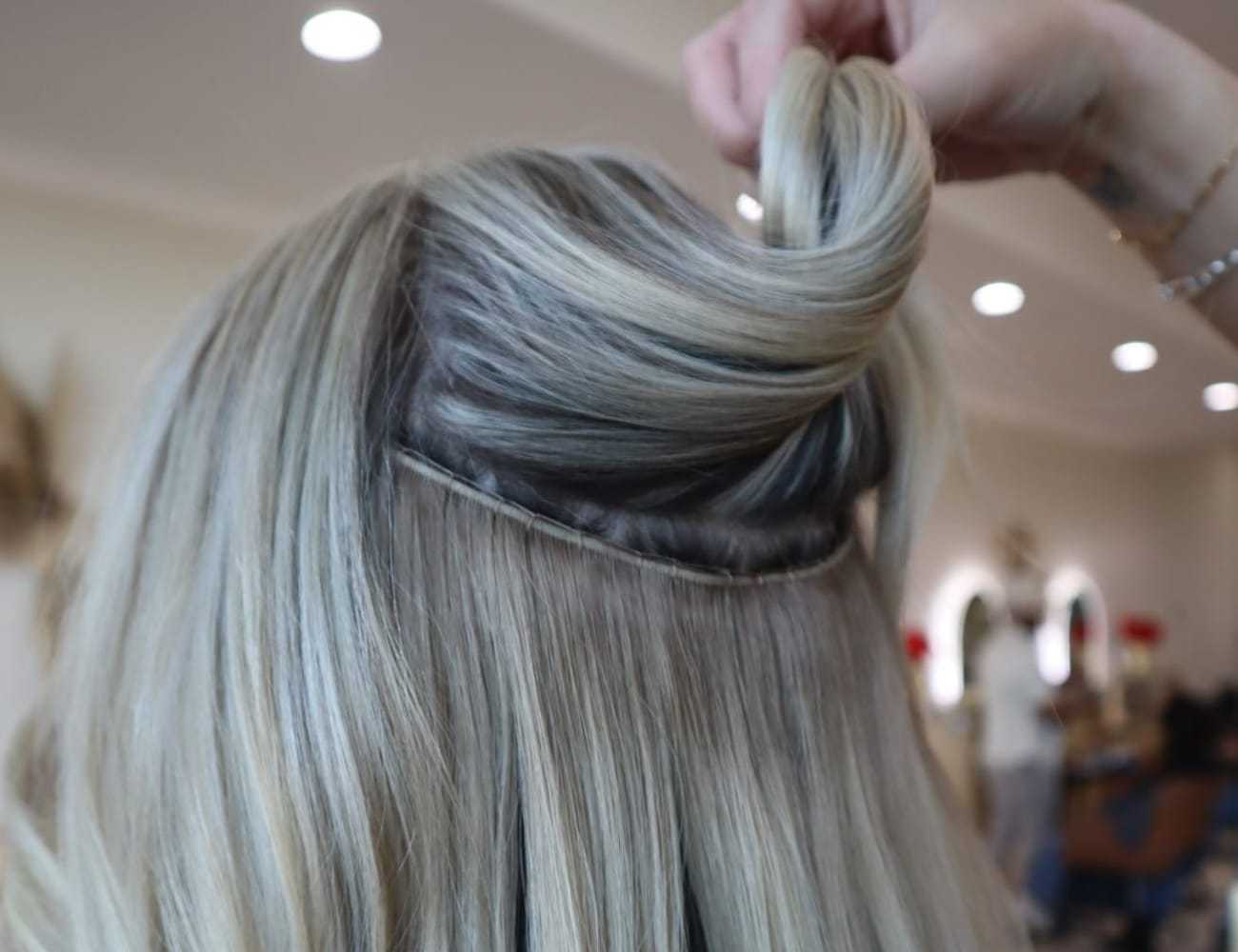 Hair stylist attaching extensions to a client in a salon setting.