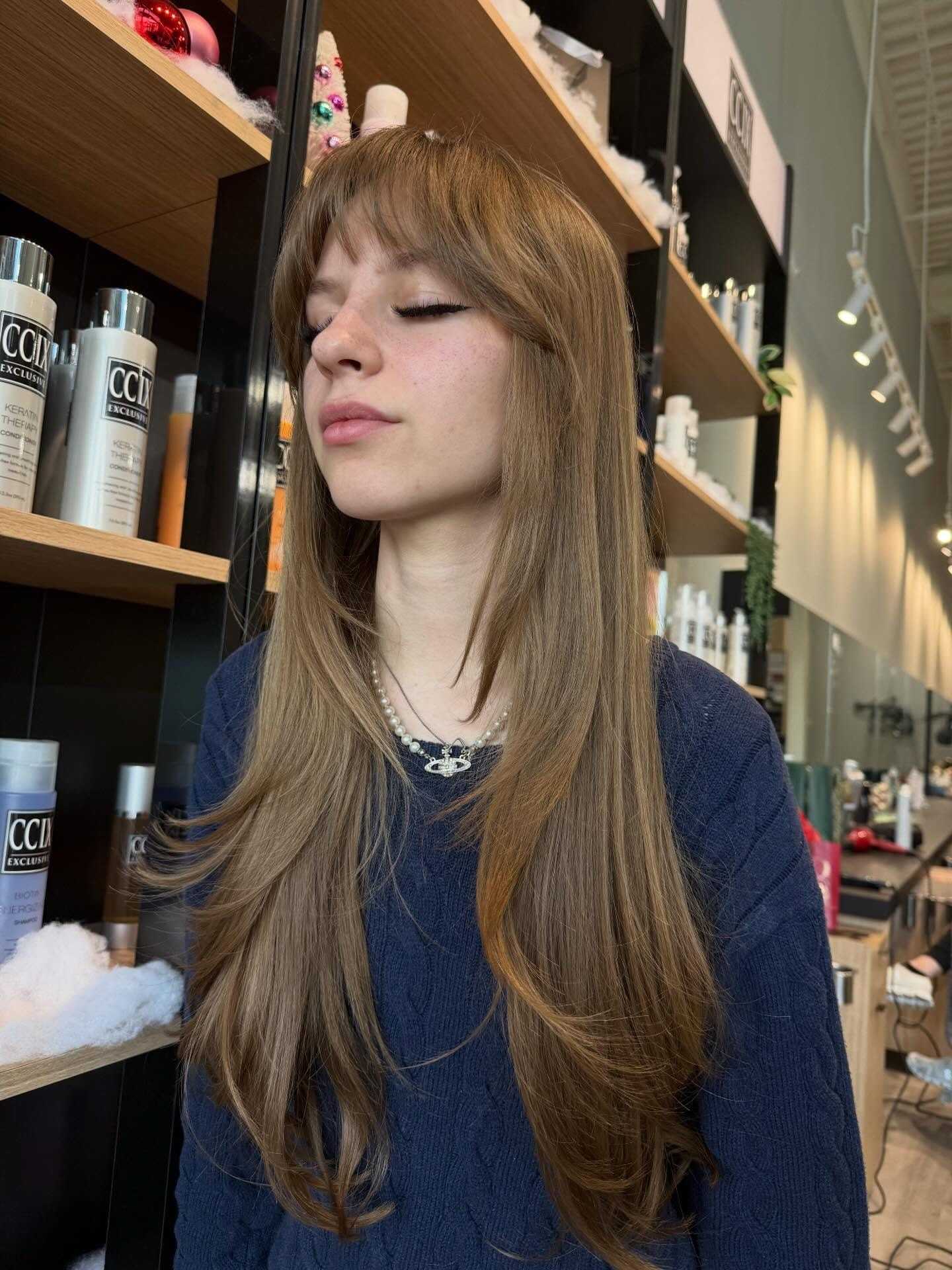 Young person with long, straight hair in a salon setting.