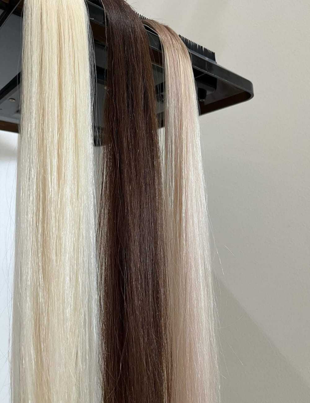 Three hair color samples: platinum blonde, brunette, and ash blonde on a display stand.