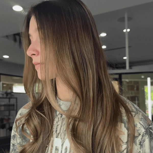 Young woman with long, wavy hair in a salon setting.